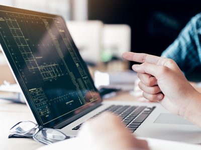 Teenagers develop programming with blueprint code in laptop monitor.